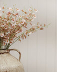 Wild Orchid Spray by Faire in a rustic ceramic vase on light paneled walls, styled for elegant living spaces.