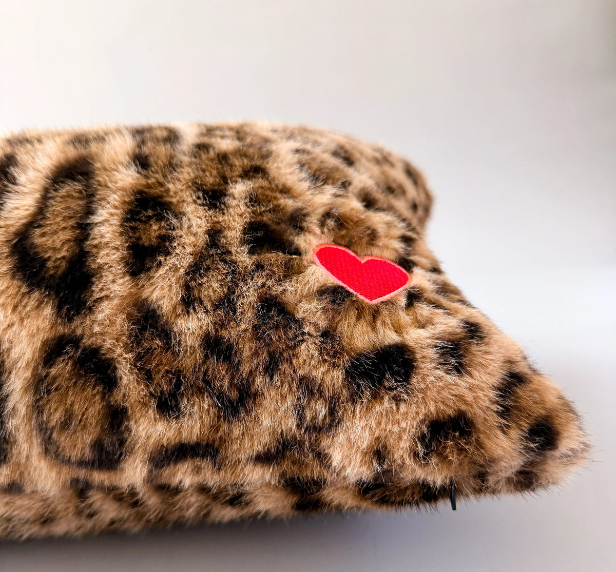 Leopard print lumbar pillow with red heart patch in faux fur by Faire, ideal for accenting sofas or beds.