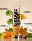 A tube of Faire Vaca Skin Redness Recovery stands upright, surrounded by leaves, calendula flowers, and nuts—featuring Centella Asiatica and ceramides to hydrate sensitive skin and promote a healthy, well-traveled glow.