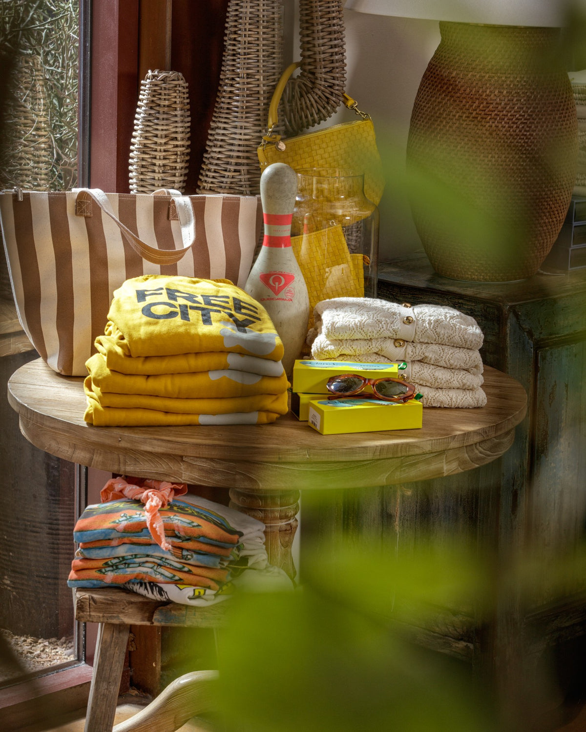 Bright summer linens and accessories from Bungalow Furniture on a wooden table by a sunlit window.