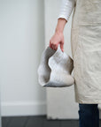 Claribel Vase Tall by Accent Decor, sculptural wavy ceramic, held by person in beige apron indoors.