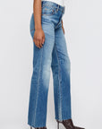 Wearing Moussy's Asheville Remake Flare jeans—lightweight blue denim with a raw hem—styled with a white top and pointed brown heeled boots, standing against a plain light background.