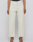 A person stands against a plain light background wearing Moussy Pomonok Gusset Cargo jeans in off-white with front patch pockets, paired with a black top and black pointed-toe heels.