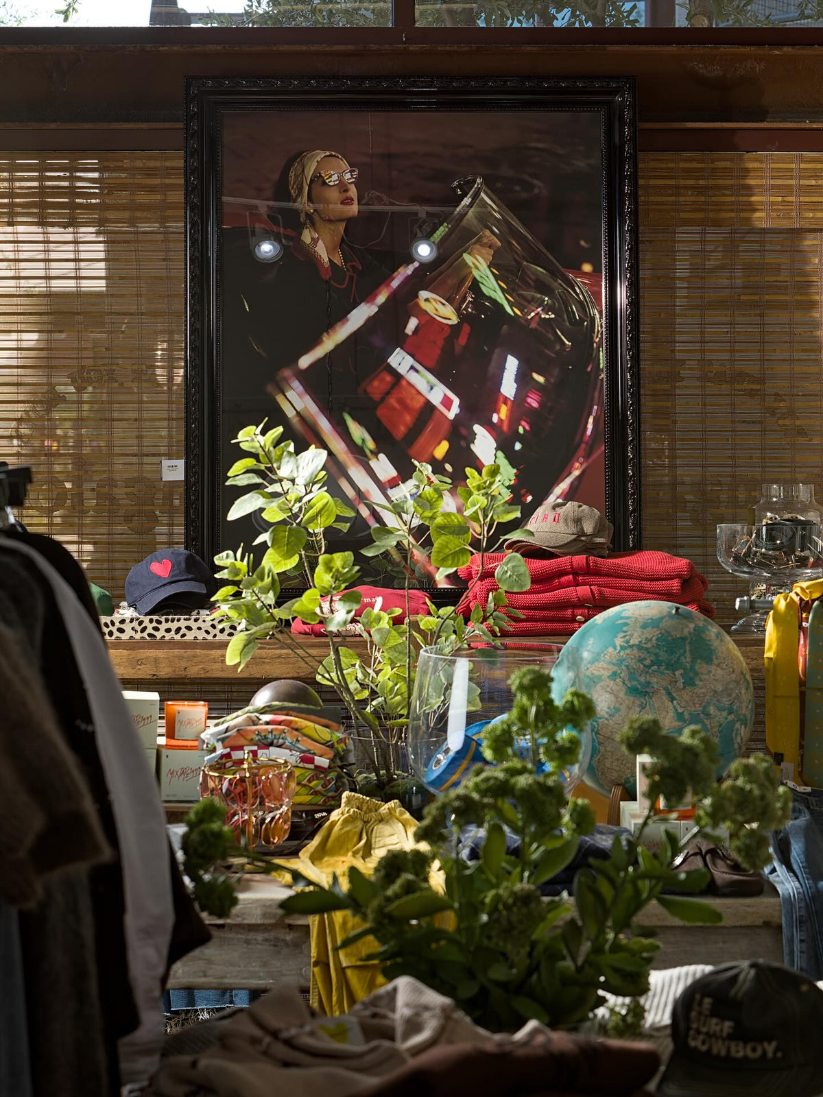 Eclectic tabletop display with plants, globe, and textiles in sunlit Bungalow Furniture & Accessories showroom.