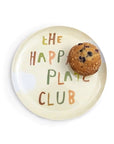The Breakfast Club Plate Set by Sugarboo Designs features a beige plate with colorful "The Happy Plate Club" text and a blueberry muffin on the upper right, perfect for a champion-worthy breakfast.