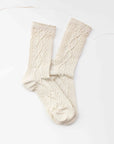 Faire Twist Cotton Crew Socks in cream feature a textured cable knit pattern and are shown overlapping on a white surface.