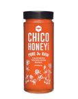 A tall glass jar with a black lid, filled with golden honey. The label reads "Olivarez Chico Honey" by Faire and features white floral illustrations at the bottom.