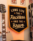 Black and gold camp flag by The Faire displayed beside a stickered guitar case for a creative home decor touch.