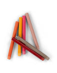 The Faire Warm Colours Dinner Candles S/2 are hand-poured in vibrant shades and displayed in a loose, overlapping cluster on a white background.