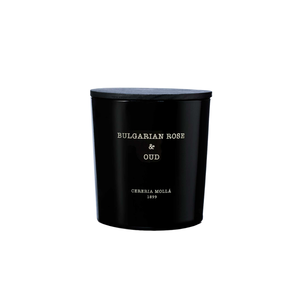 A black candle jar with a matching lid displays “Bulgarian Rose & Oud” and the Cereria Molla brand on white text. This elegant soy wax scented candle is showcased against a plain, light background.