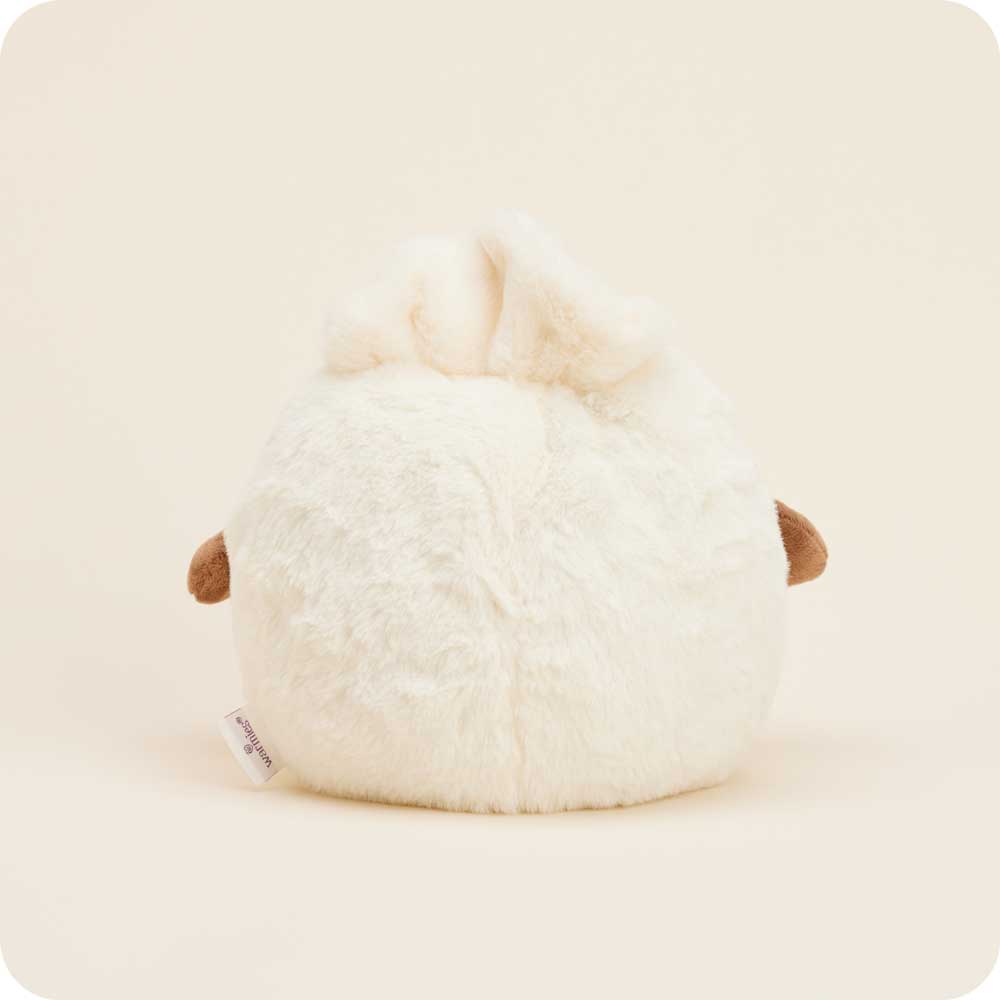 The Dumpling Warmies by Faire is a round, fluffy white microwavable plush toy with small brown wings and a tuft on top. Shown from the back against a beige background, it’s perfect for cozy comfort.