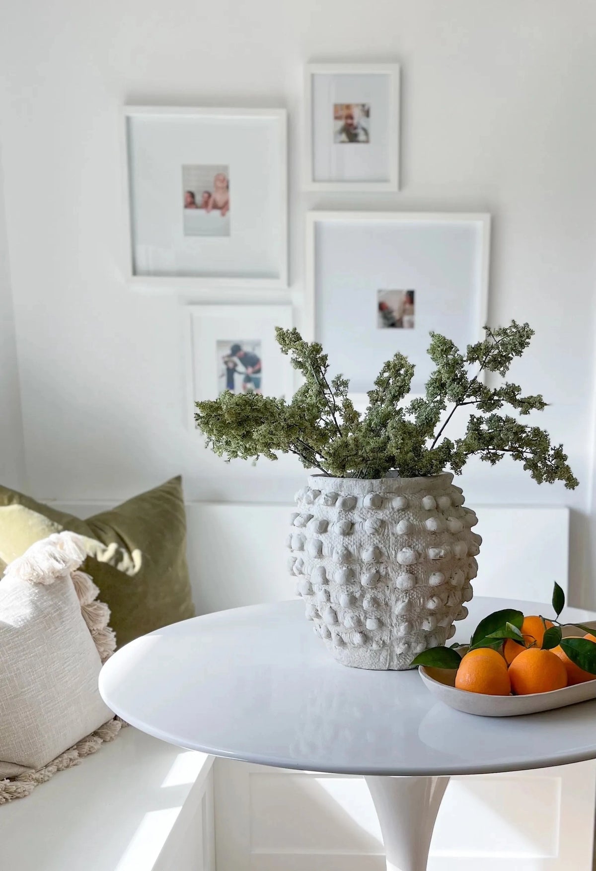 Faux Sage Moss Spray 33″ in a textured white vase on a table with oranges, Bungalow Furniture &amp; Accessories style.