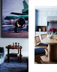A modern space featured in "Robert Stilin New Work" by Hachette Book Group includes a dark plush chair, round table, aviation-themed art, and a kitchen with blue cabinets, stainless appliances, and a fruit- and flower-topped wood dining table.