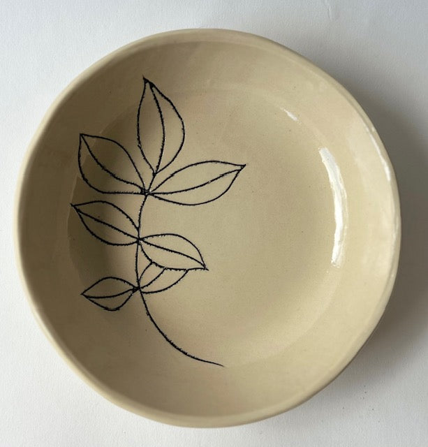 The Faire Floral 6" Tree Bowl is a cream-colored handmade stoneware bowl with a simple black line drawing of five overlapping leaves inside and an artisanal shape—perfect for any kitchen or dining table.