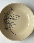 The Faire Floral 6" Tree Bowl is a cream-colored handmade stoneware bowl with a simple black line drawing of five overlapping leaves inside and an artisanal shape—perfect for any kitchen or dining table.