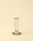 The Vero Glass Candlestick S by Indaba features a slender, rounded stem and is crafted from handblown recycled glass, offering a sustainable and timeless candle holder. Displayed on a plain, cream-colored background.