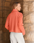 Rowan button-up jacket in coral orange with a raw hem worn over light pants from Bungalow Furniture & Accessories.