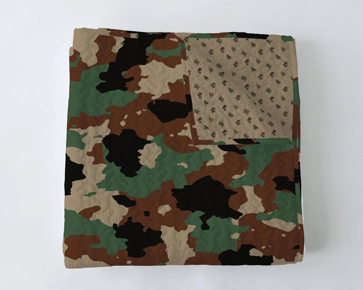 The Faire Cheyenne Camo Quilt features a green, brown, black, and tan camouflage pattern with a beige floral underside. Modern quilt fans will love this design from Fort Worth, Texas.