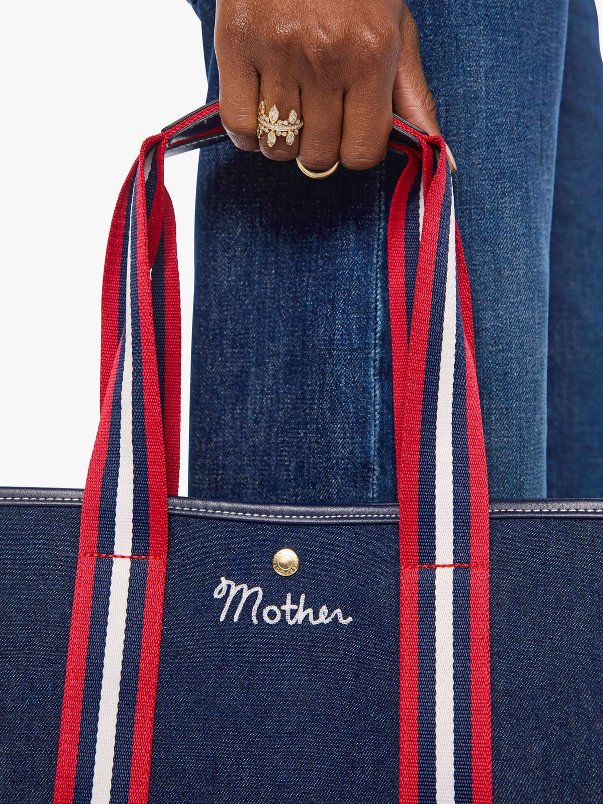 The Everywhere denim tote by Mother with red, white, and blue handles, styled with casual blue jeans.