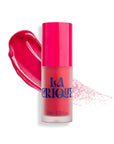 A pink bottle of Faire 04 Water Lip Balm Shade with a bright pink cap and bold blue lettering stands before a pink smear, offering a radiant matte finish for lips and cheeks.