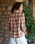 SILVIO Untuckable Button Up Shirt in tan and brown plaid worn with rolled sleeves against a stone wall.