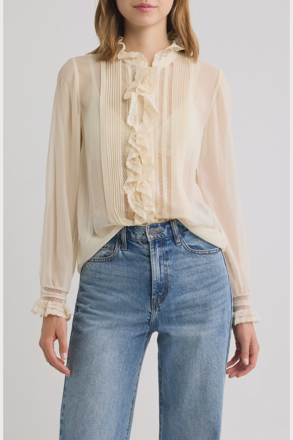 Sheer chiffon DOEN Magdeleine top with lace and ruffled collar, styled with blue high-waisted jeans.