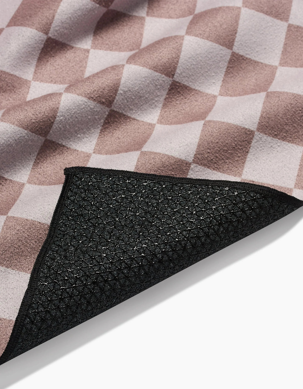 The Faire Chic Checker Yoga Towel features a soft pink and white checkerboard fabric and a black, slip-resistant rubberized underside, shown partially folded.