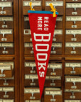The Faire Read More Books Pennant features red felt with "READ MORE BOOKS" in white letters and blue and yellow ribbons, hanging on a wooden card catalog to inspire book lovers.