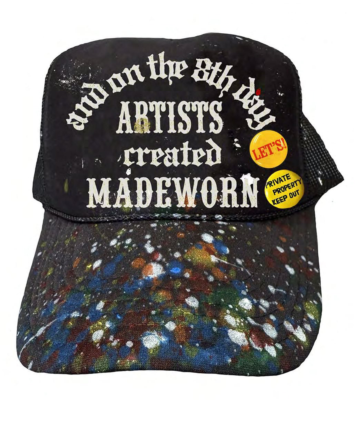 The Made Worn 8th Day Artist Hat is a hand-painted black trucker hat with colorful paint splatters, "and on the 8th day ARTISTS created MADEWORN" text, and two yellow pins that say “LET'S!” and “PRIVATE PROPERTY KEEP OUT.”.