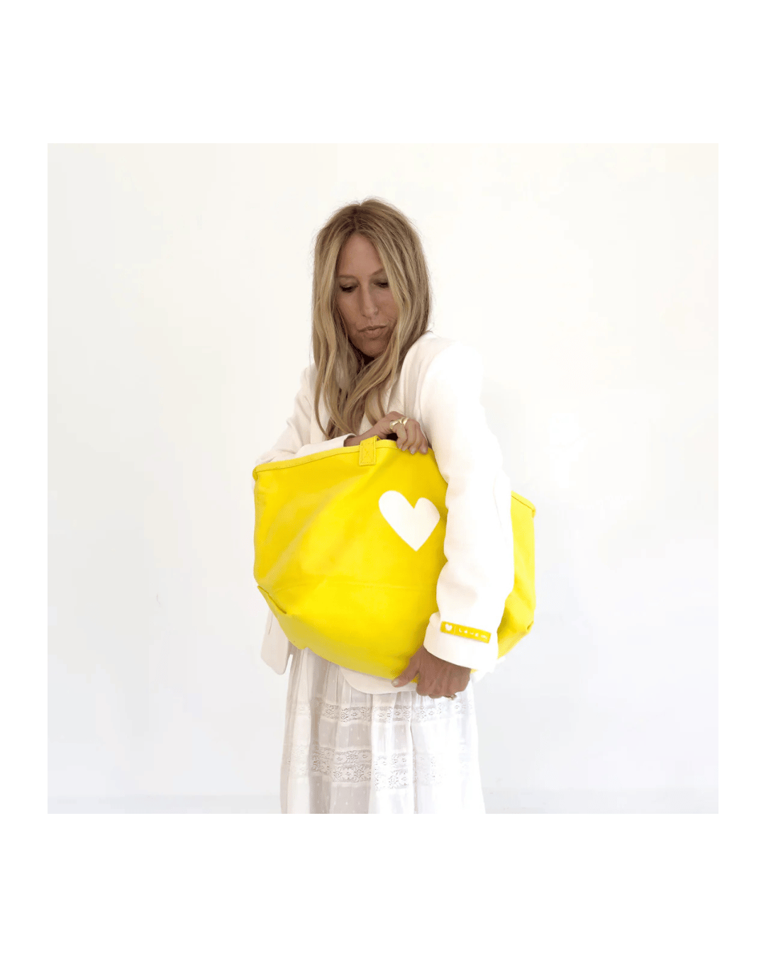 Yellow KR Imperfect Heart Tote by Kerri Rosenthal with a leather heart charm, styled by woman in white.