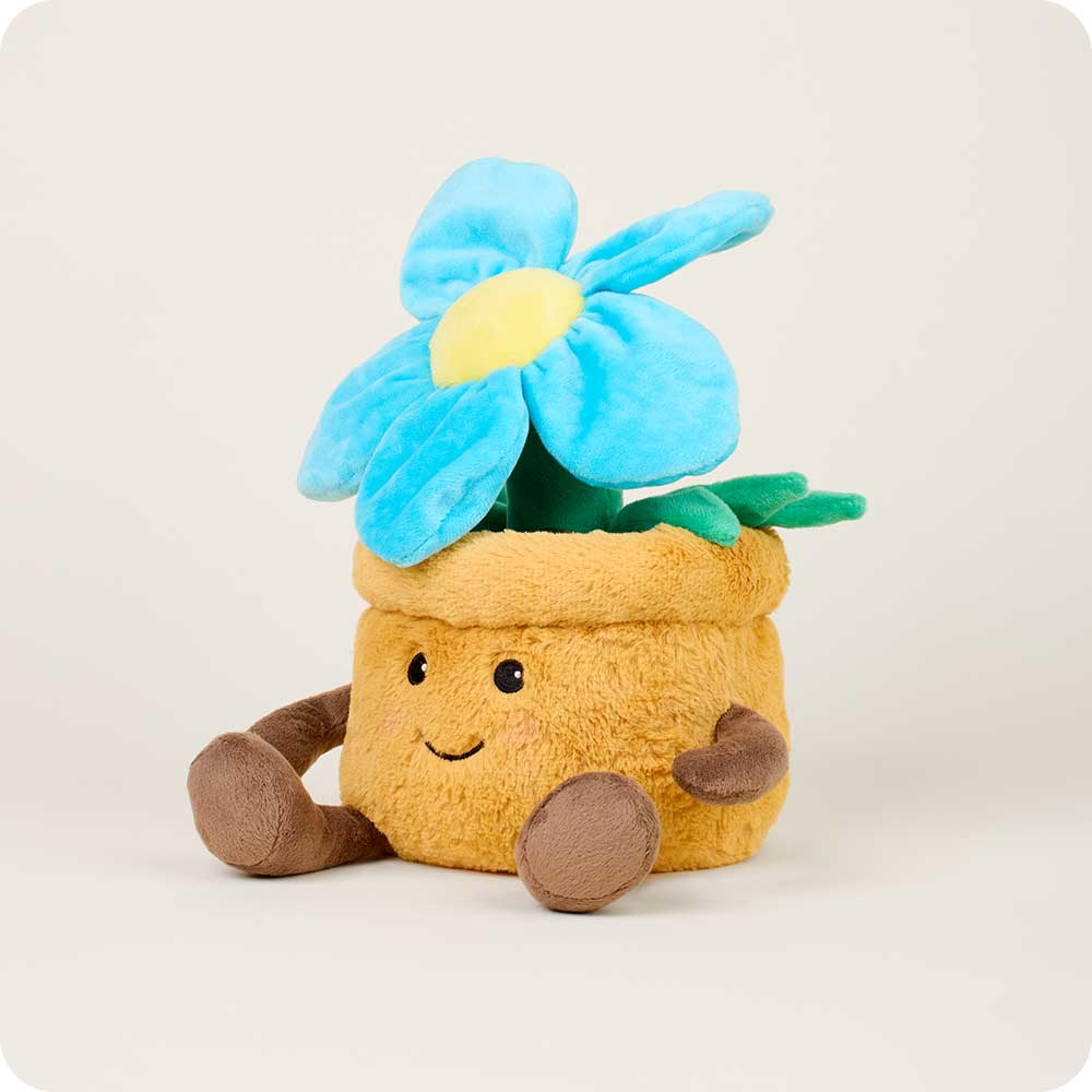 The Blue Flower Pot Warmies by Faire is a microwavable plush shaped like a smiling brown flowerpot with arms, legs, and a large blue and yellow flower, offering cozy comfort against a plain light background.