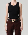 A person wearing the Citizens Of Humanity/AGOLDE nova tank, styled with high-waisted dark red pants, a black belt with a gold buckle, and gold jewelry, stands against a plain light background.