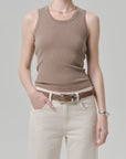 Wearing the Citizens Of Humanity/AGOLDE nova tank, beige jeans, a brown belt, silver bracelet, and thin necklace, a person stands with one hand in their pocket against a plain light gray background.