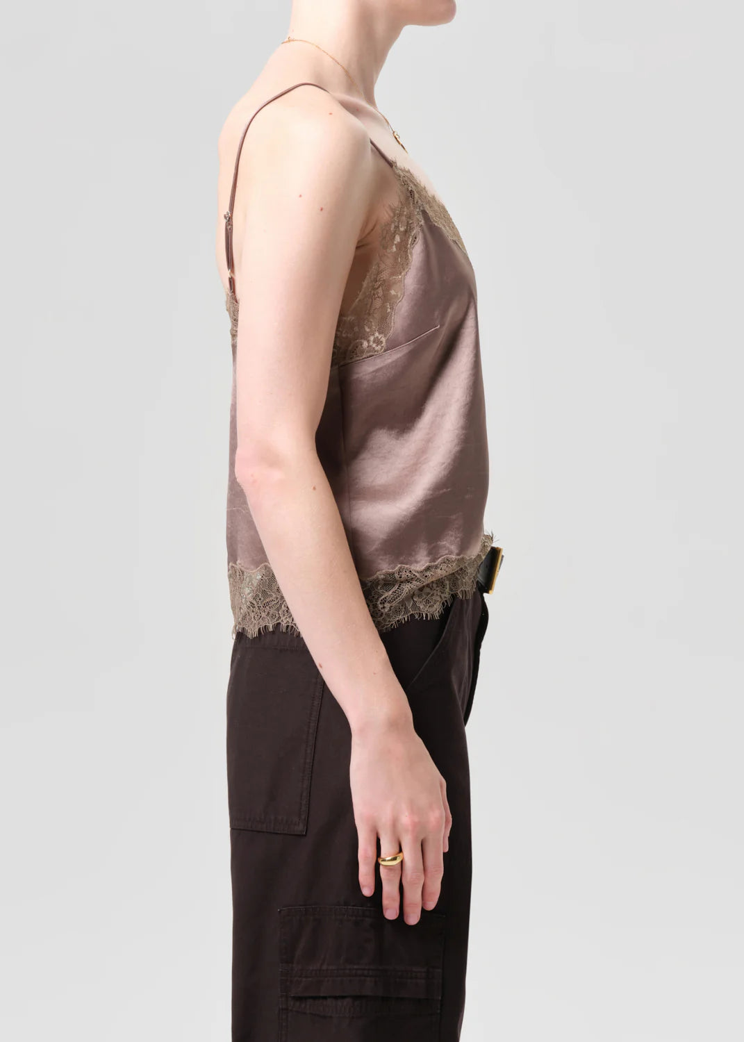 A person in profile wears a Citizens Of Humanity/AGOLDE lace trimmed cami with dark high-waisted pants against a plain light gray background.
