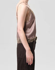 A person in profile wears a Citizens Of Humanity/AGOLDE lace trimmed cami with dark high-waisted pants against a plain light gray background.