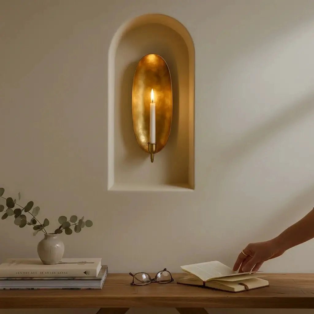 Brass wall candle sconce by Faire casts a warm glow above a cozy, styled wooden table at Bungalow Furniture &amp; Accessories.