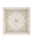 The Silk Bandana by The Great Inc. is a white silk accessory adorned with black and gold paisley and floral motifs, a bold central circular floral design, and ornate borders—a timeless homage to vintage bandanas.