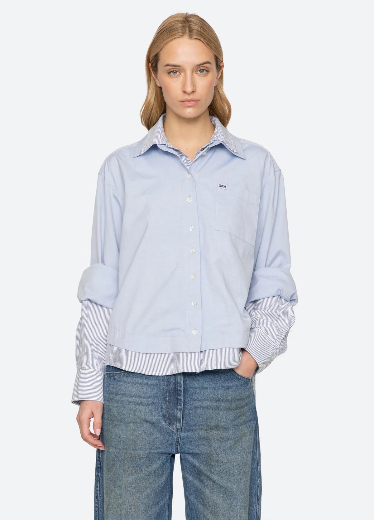 Sea New York Zayna Button Down shirt in light blue with layered hem and striped cuffs, styled with blue jeans.