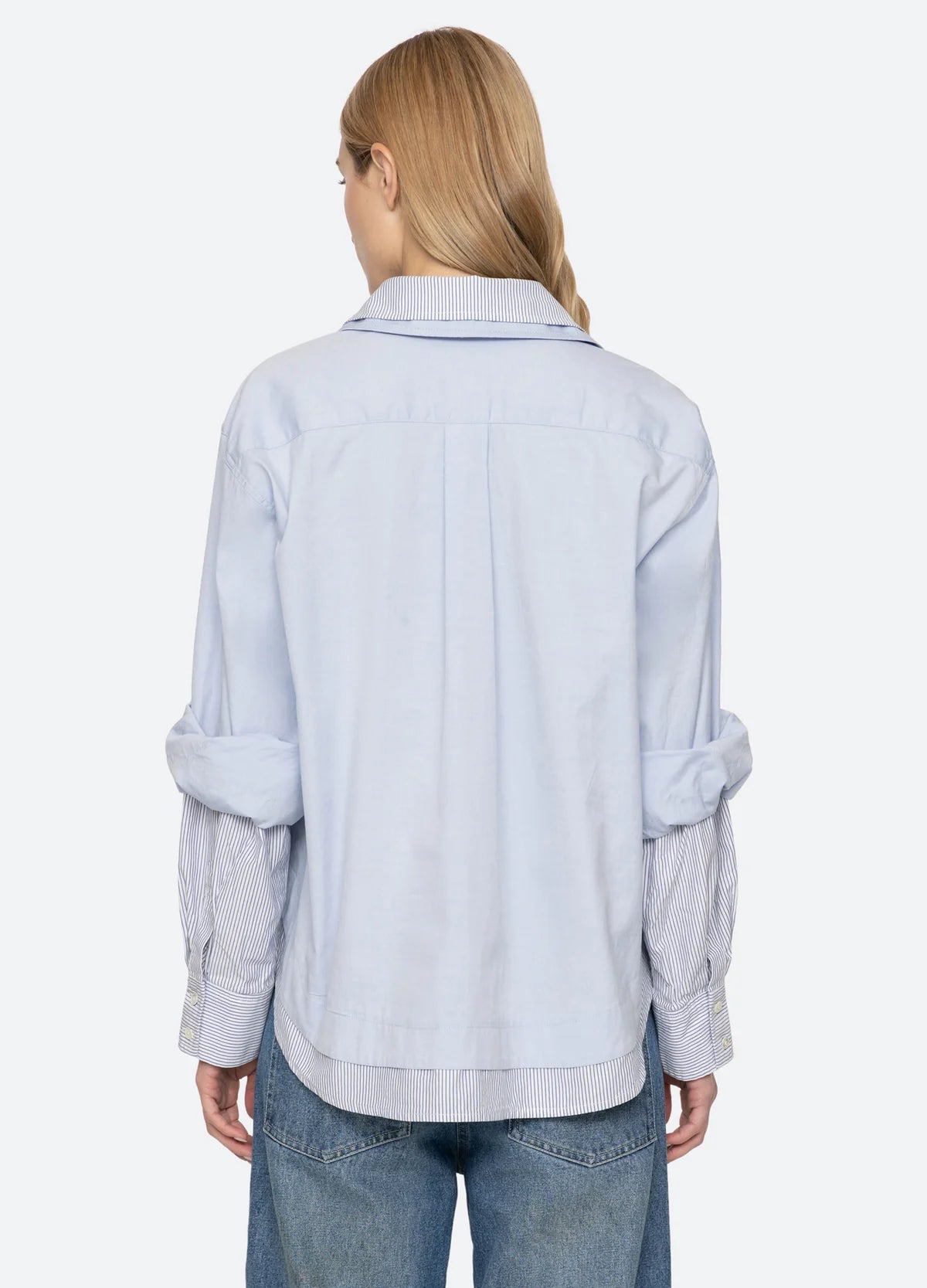 Oversized light blue Zayna Button Down with striped collar and cuffs, back view paired with jeans.