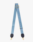 The Clare Vivier Adjustable Crossbody Strap features light blue cotton webbing, gold clips, black leather ends, and "CIAO" printed in white along the length.
