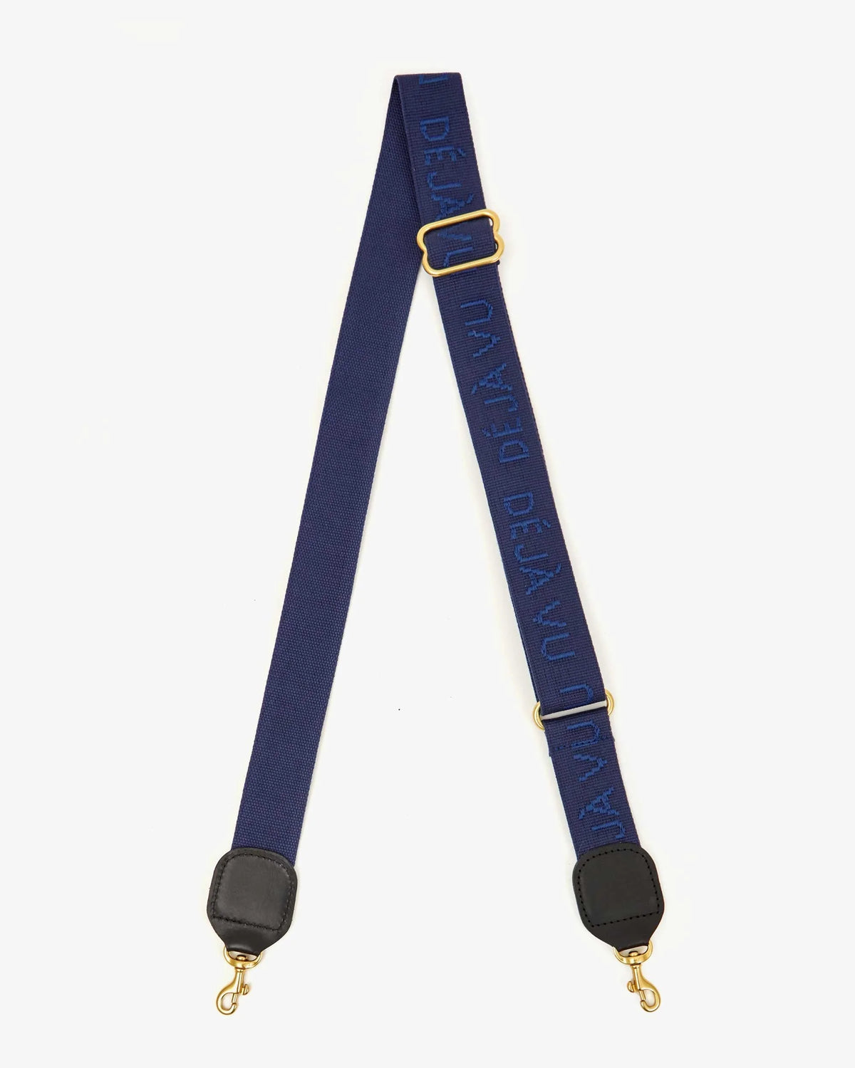 The Clare Vivier Adjustable Crossbody Strap features blue cotton webbing, gold-tone clasps, black leather trim, and raised “DÉJÀ VU” lettering in blue.
