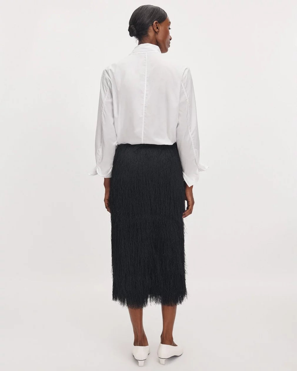 Amalia fringe midi skirt in black styled with a white button-down shirt and heels.