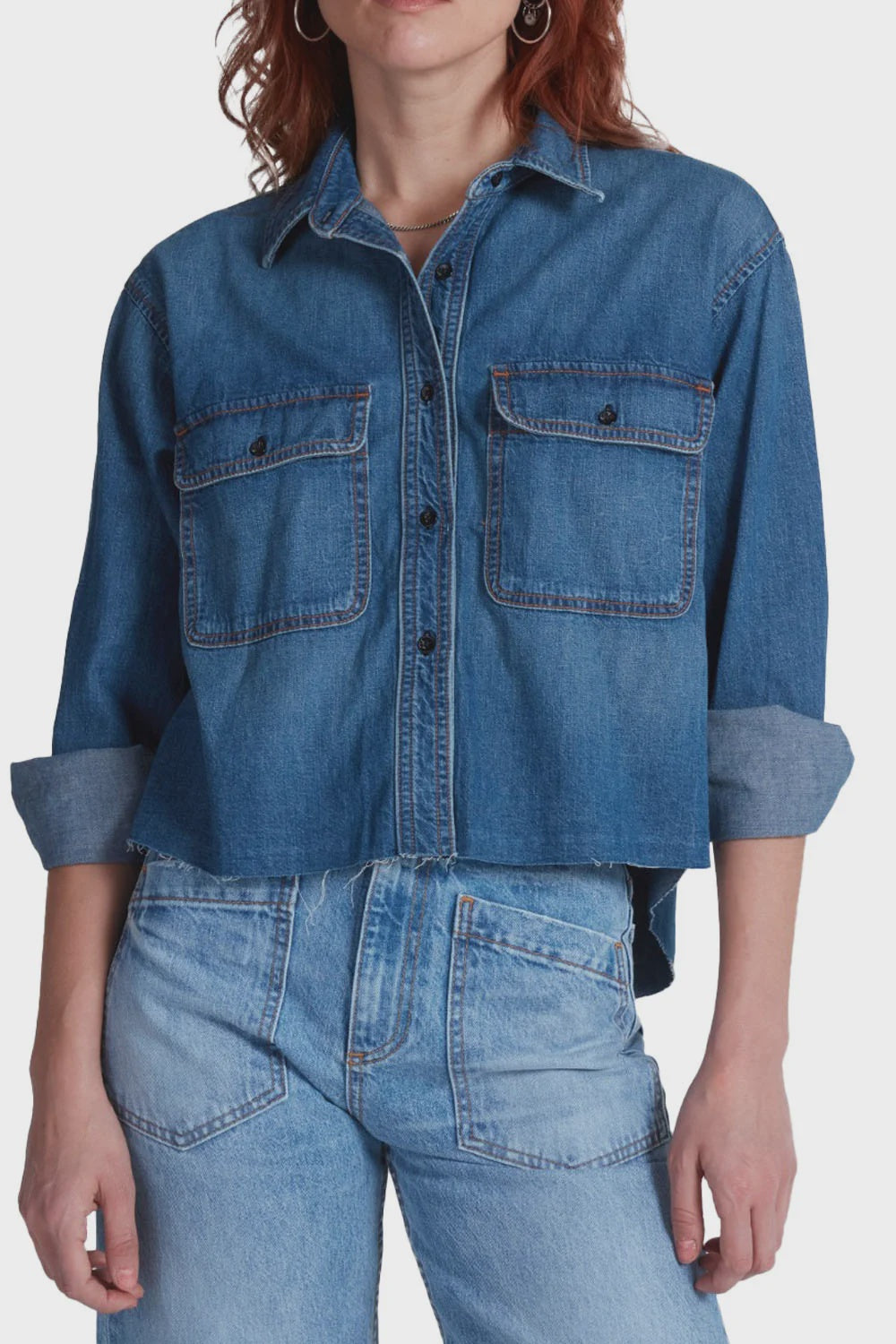 Cropped blue denim ASKK Crosby Gunnsion shirt featuring two chest pockets and a raw-edge hem.