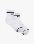 The Mother Baby Steps Ankle socks feature classic black and white tube sock styling, with "MO" on one cuff and "FUC" on the other, shown against a plain white background.