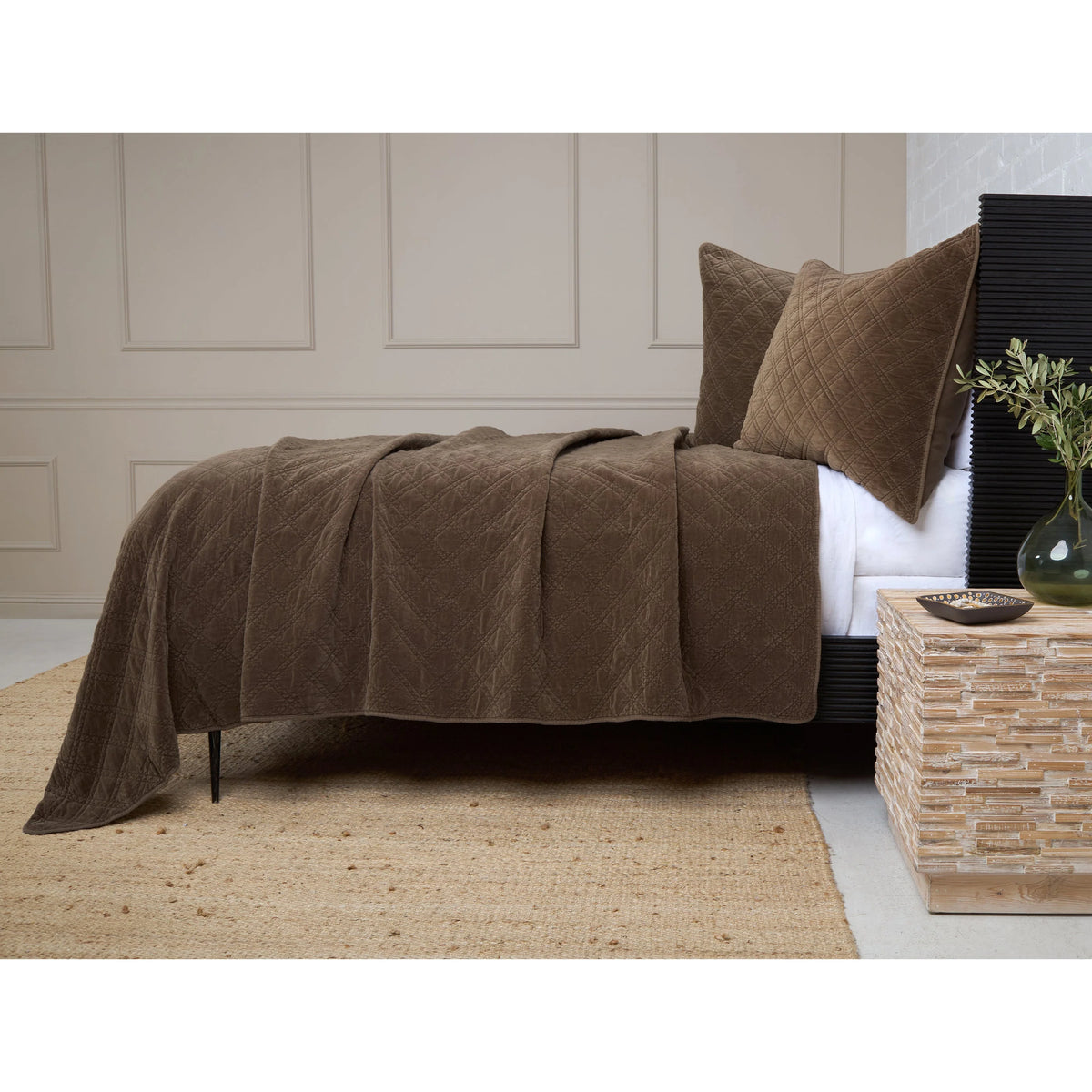 Diamond-quilted brown cotton velvet coverlet by POM POM with matching pillow on a woven rug.