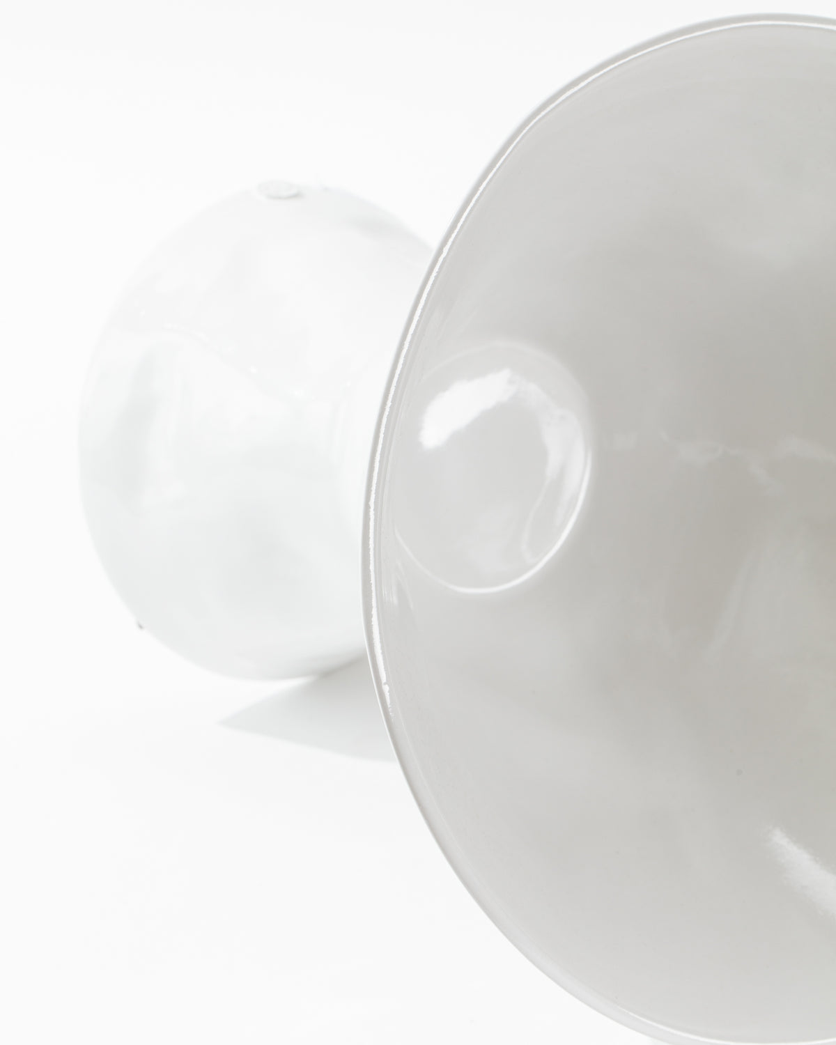 A close-up photograph of the Catchall Bowl No. 979 by Montes Doggett reveals a high-fired ceramic piece with a smooth, glossy surface. The image captures the bowl in detail, emphasizing its clean, reflective finish. Made in Peru, this pristine piece showcases exceptional craftsmanship. The minimal white background highlights the bowl's shape and texture.