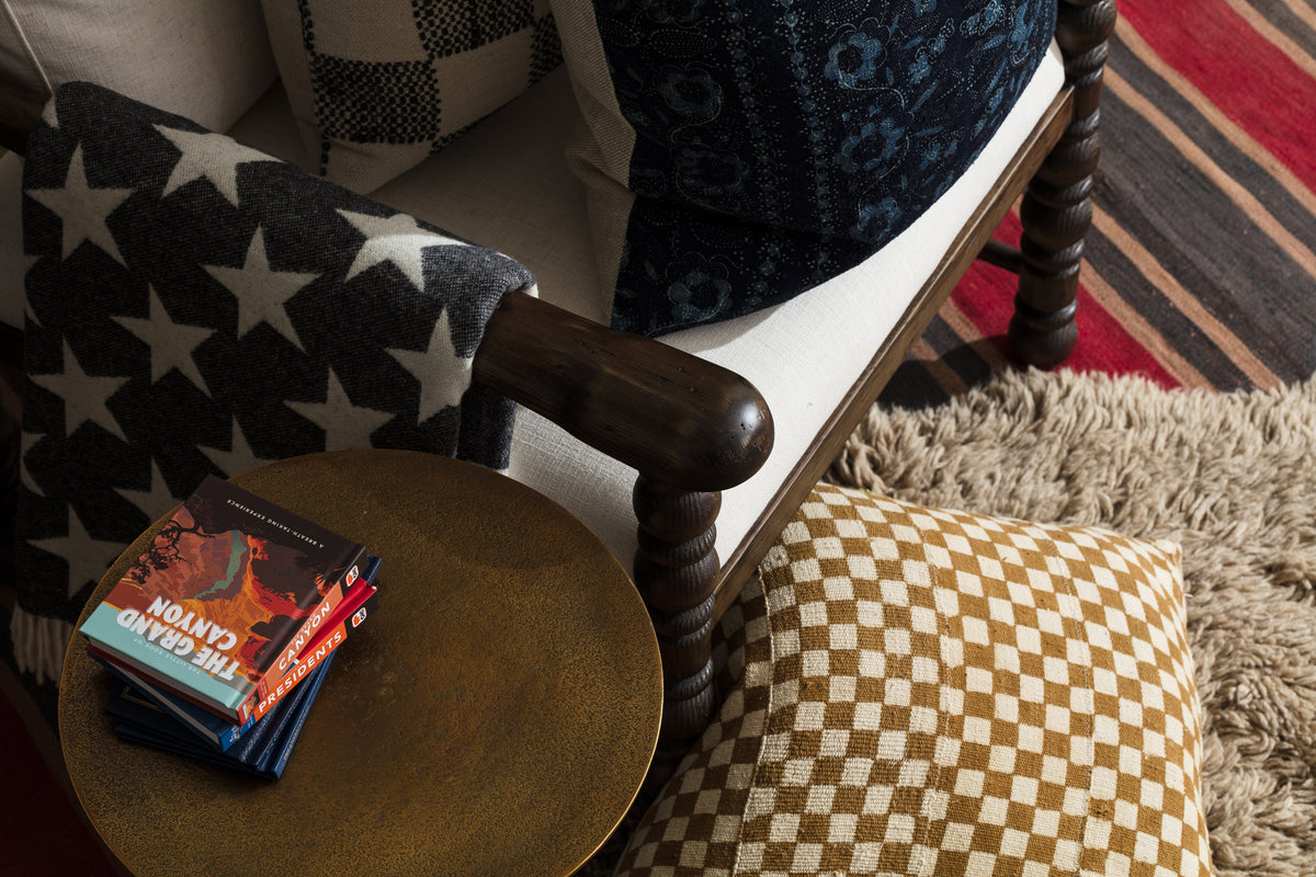 Bungalow Furniture cozy reading nook with star and checkered pillows on a striped shaggy rug beside a round table.