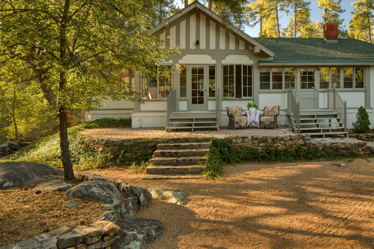 Cozy porch scene with two chairs and table by Bungalow Furniture, surrounded by trees in warm natural sunlight.