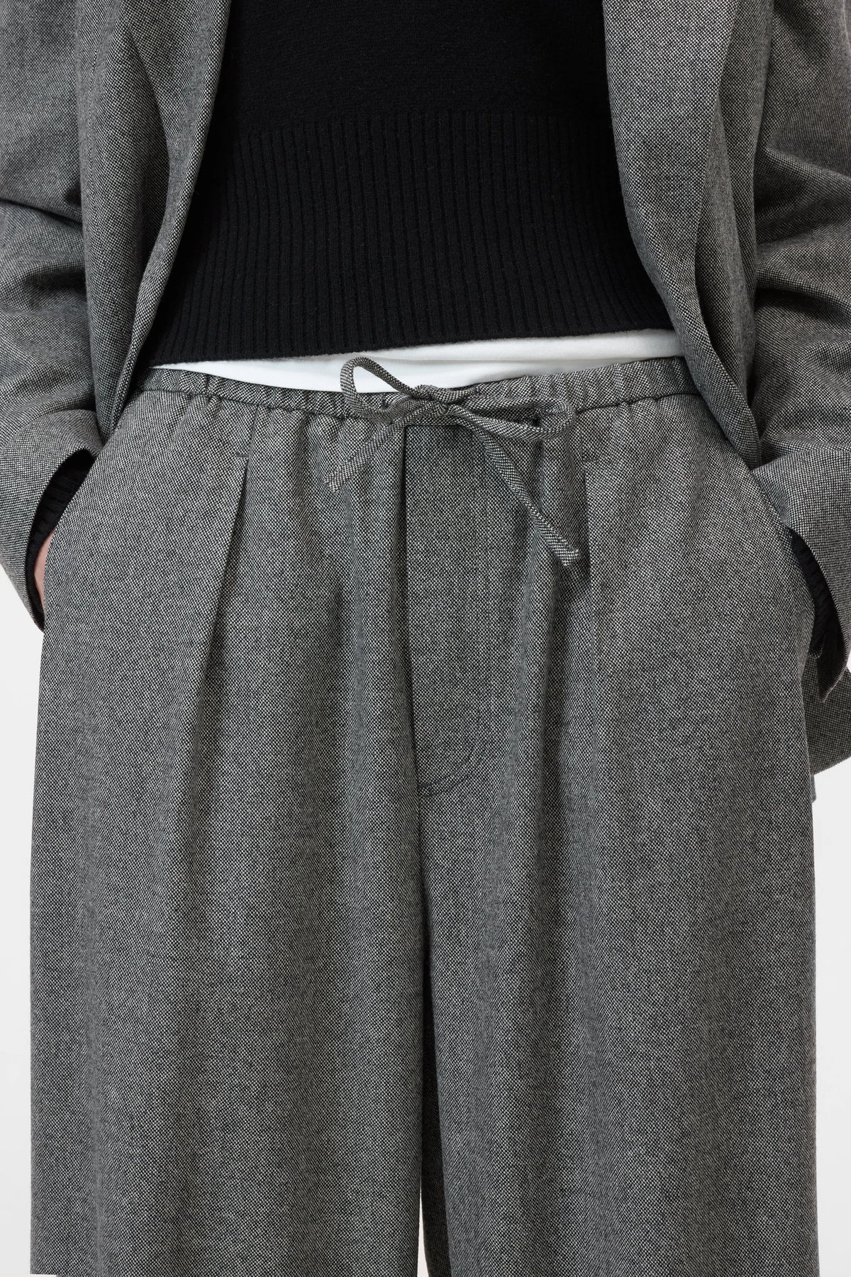 Grey CLOSED Wynston relaxed fit flannel trousers styled with a black sweater and grey blazer, hands in pockets.