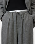 Grey CLOSED Wynston relaxed fit flannel trousers styled with a black sweater and grey blazer, hands in pockets.